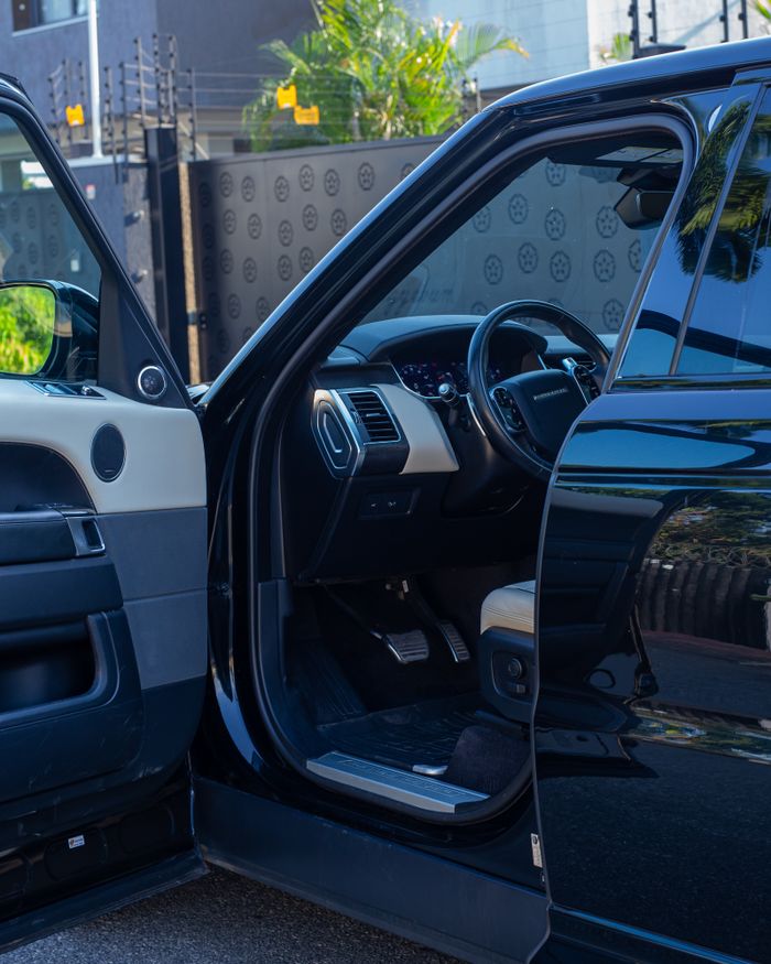 Home High-end black vehicle with an open door showcasing sleek interior design and exterior reflections.