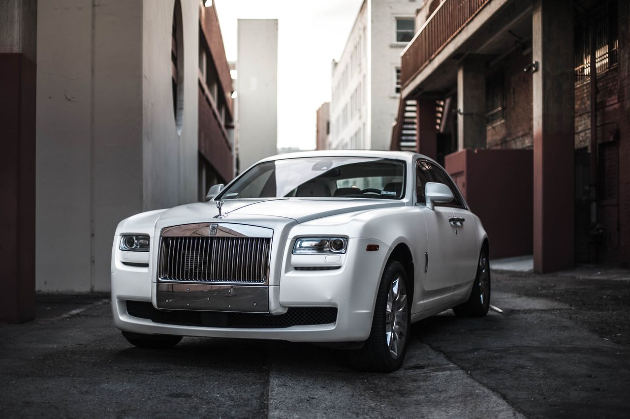 Home Elegant white luxury car parked in an urban alley, exuding sophistication and style.