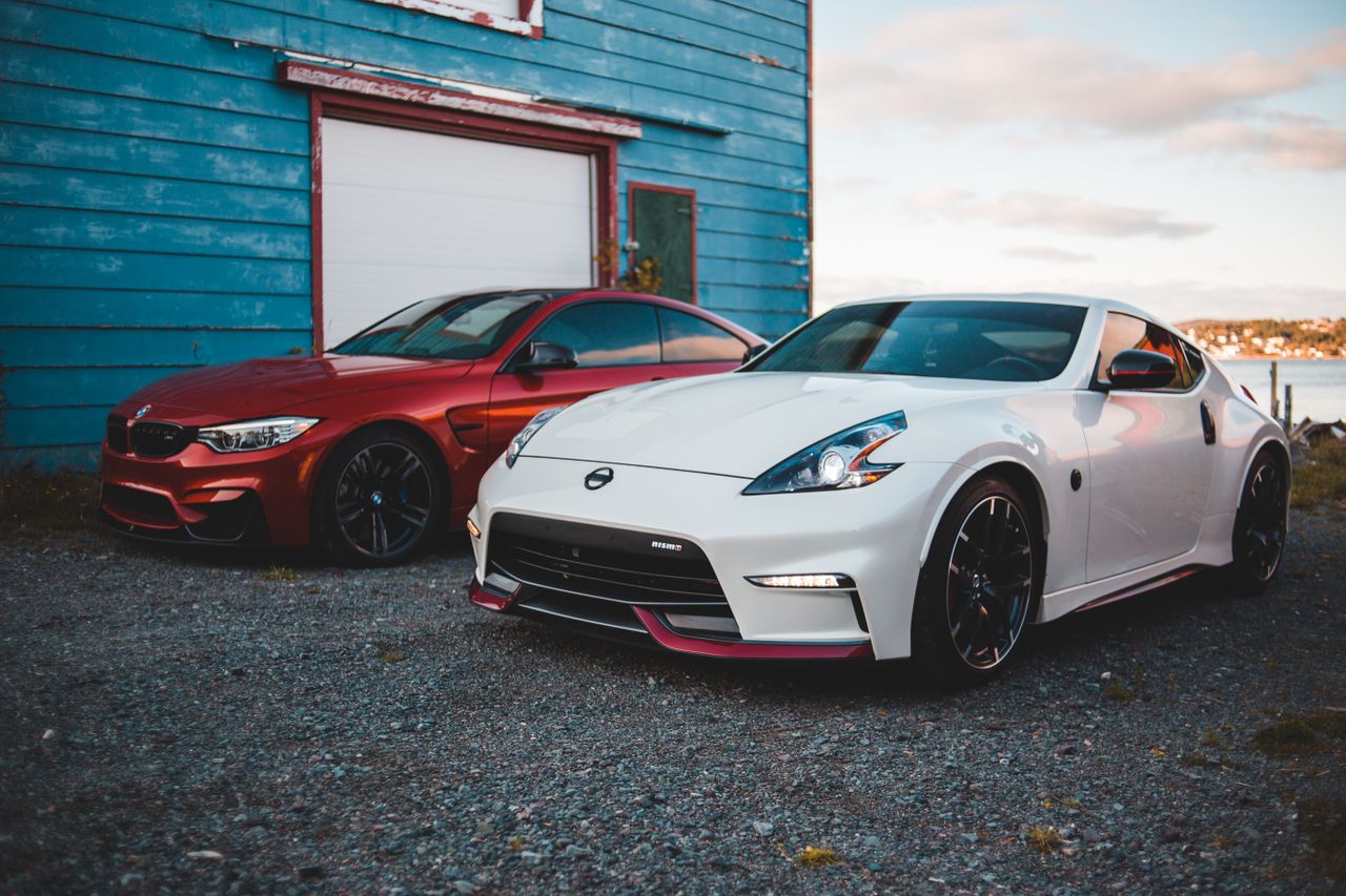 Services Stylish shiny tuned red and white sports cars parked near rustic barn at lakeside in suburb area